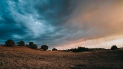 dirt field under cloudy sky during daytime